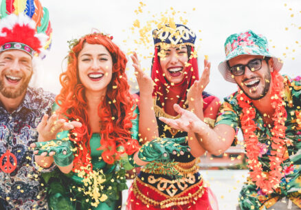 Happy dressed people celebrating at carnival party throwing confetti - Young friends having fun together at fest event - Youth, hangout, festive and happiness concept - Focus on left couple hands